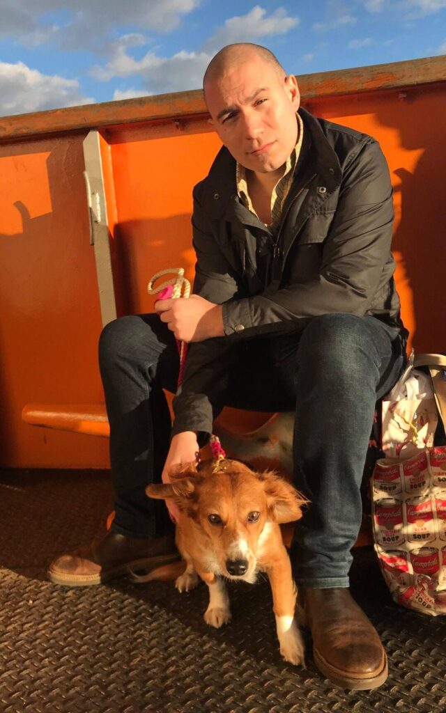 An artist photo of a handsome motion designer, seated, with a beautiful dachshund.